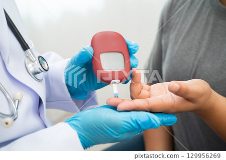 Doctor check diabetes from finger blood sugar level with digital glucose monitor measure and test stripe. 129956269