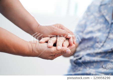 Caregiver holding hands Asian elderly woman patient, help and care in hospital. 129956290