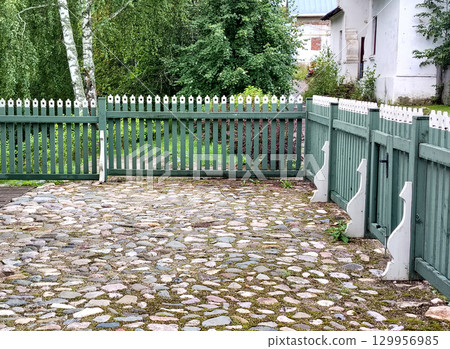 A neatly manicured farmyard, cobbled and enclosed by a wooden fence 129956985