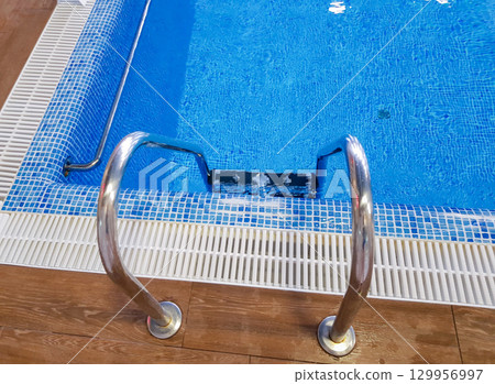 Top view of the metal stairs going down to the pool 129956997