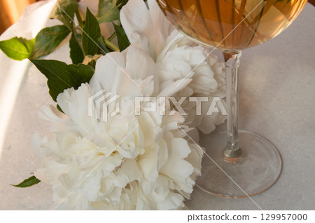 White wine in the glass and peony flowers. Romantic dinner White wine in the glass and peony flowers. Romantic dinner 129957000