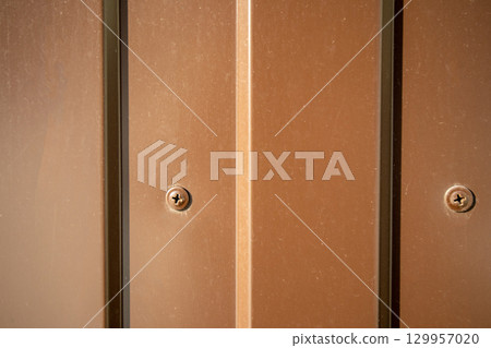 Brown industrial background self-tapping screw in corrugated sheet close-up 129957020