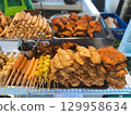 Thai street food stall with meat skewers, spring rolls and sausages. Concept of culture, tradition, taste, lifestyle and culinary experience. 129958634