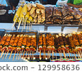 Thai street food stall with grilled meat and corn on skewers. Concept of culture, tradition, nutrition, flavor, community and culinary lifestyle. 129958636