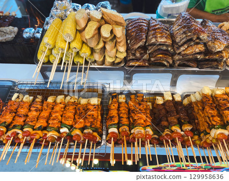 Thai street food stall with grilled meat and corn on skewers. Concept of culture, tradition, nutrition, flavor, community and culinary lifestyle. Thai street food stall with grilled meat and corn on skewers. Concept of culture, tradition, nutrition, flavor, community and culinary lifestyle. 129958636