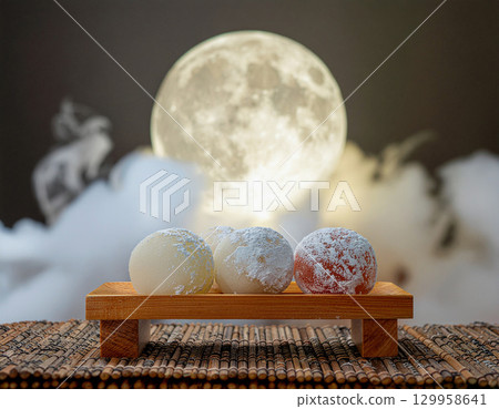 Traditional Tsukimi Dango rice dumplings lined up against a full moon and clouds 129958641