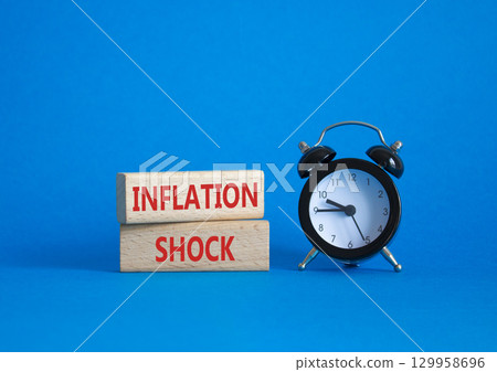 Inflation Shock symbol. Concept word Inflation Shock on wooden blocks. Beautiful blue background with alarm clock. Business and Inflation Shock concept. Copy space Inflation Shock symbol. Concept word Inflation Shock on wooden blocks. Beautiful blue background with alarm clock. Business and Inflation Shock concept. Copy space 129958696