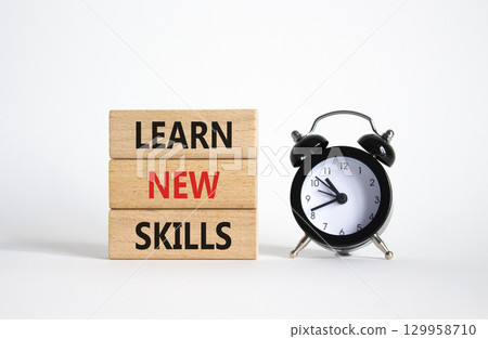 Learn new skills symbol. Concept words Learn new skills on wooden blocks. Beautiful white background with alarm clock. Business and Learn new skills concept. Copy space. 129958710