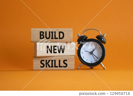 Build New skills symbol. Concept word Build New skills on wooden blocks with alarm clock. Beautiful orange background. Business and Build New skills concept. Copy space 129958718