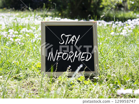 Stay Informed symbol. Concept word Stay Informed on chalk blackboard. Beautiful meadow background. Business and Stay Informed concept. Copy space. 129958747