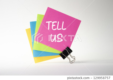 Tell us symbol. Pink sticky note with words Tell us. Beautiful white background. Business and Tell us concept. Copy space. 129958757