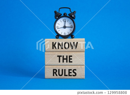 Know the rules symbol. Wooden blocks with words Know the rules. Beautiful blue background with alarm clock. Business and Know the rules concept. Copy space. 129958808