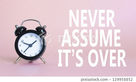 Never assume it is over symbol. Beautiful pink background with alarm clock. Business and Never assume it is over concept. Copy space. 129958852