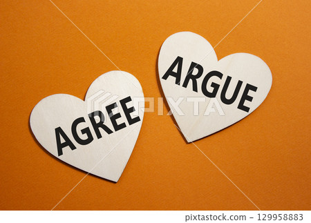 Agree or Argue symbol. Concept word Agree or Argue on wooden hearts. Beautiful orange background. Business and Agree or Argue concept. Copy space Agree or Argue symbol. Concept word Agree or Argue on wooden hearts. Beautiful orange background. Business and Agree or Argue concept. Copy space 129958883
