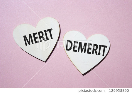 Merit or Demerit symbol. Concept word Merit or Demerit on wooden hearts. Beautiful pink background. Business and Merit or Demerit concept. Copy space 129958890