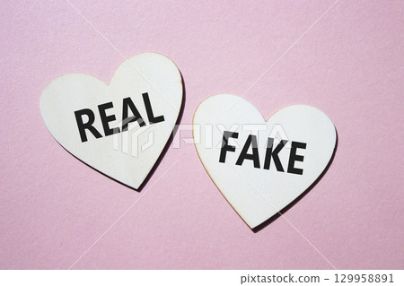 Real or Fake symbol. Concept word Real or Fake on wooden hearts. Beautiful pink background. Business and Real or Fake concept. Copy space Real or Fake symbol. Concept word Real or Fake on wooden hearts. Beautiful pink background. Business and Real or Fake concept. Copy space 129958891