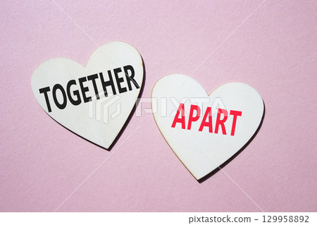 Together or Apart symbol. Concept word Together or Apart on wooden hearts. Beautiful pink background. Business and Together or Apart concept. Copy space 129958892
