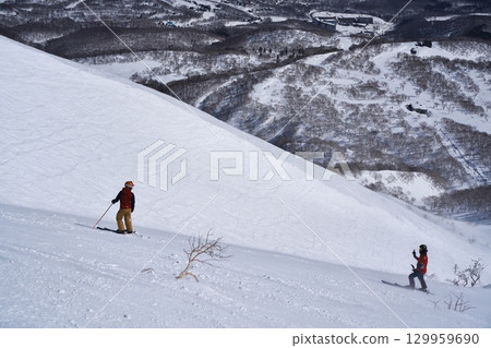 Skiers skiing from the dynamic course of Niseko Tokyu Grand Hirafu slope into the ski resort management area 129959690
