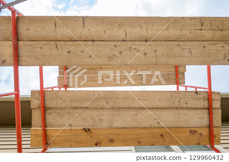 Construction scaffolding structure supports renovation work on a building exterior in daylight 129960432