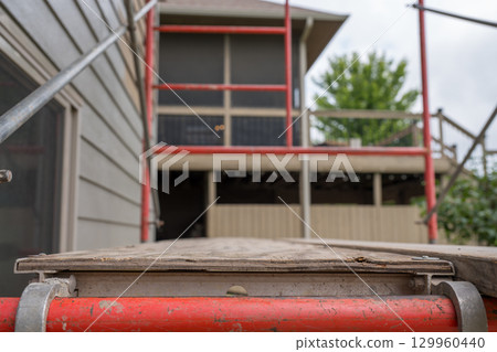 Construction scaffolding provides access for renovation of residential building in a suburban area 129960440
