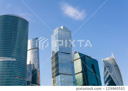 urban background, view of modern skyscrapers tops against blue sky urban background, view of modern skyscrapers tops against blue sky 129960581