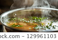 Steaming soup with fresh herbs 129961103