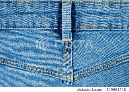 Blue denim fabric close up with seam and belt loop as textile background texture for fashion design 129961518