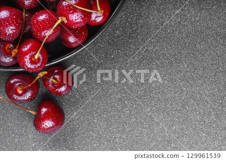 Black plate full of fresh ripe red sweet cherry and linen napkin on gray bakground with copy space Black plate full of fresh ripe red sweet cherry and linen napkin on gray bakground with copy space 129961539