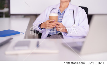 Asian Adult Female Doctor Takes Coffee Break in Modern Office Professional Healthcare Worker Relaxing During Busy Work Day Asian Adult Female Doctor Takes Coffee Break in Modern Office Professional Healthcare Worker Relaxing During Busy Work Day 129961641