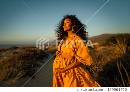 A woman in a yellow dress is standing in a field 129961730