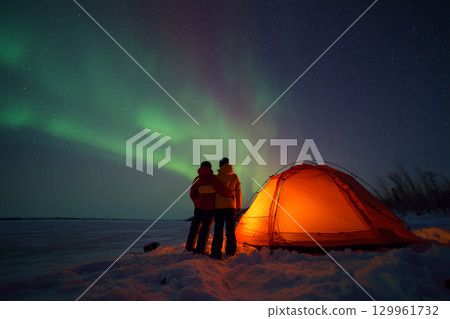 A couple is standing outside of a tent in the snow A couple is standing outside of a tent in the snow 129961732