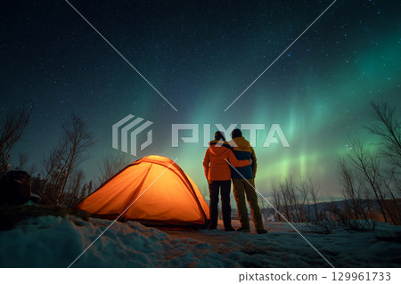A couple is standing in front of a tent in the snow 129961733