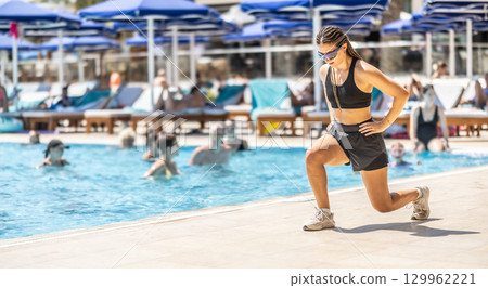 A young female Sports Animator is doing water aerobics for people in the pool of a hotel resort 129962221