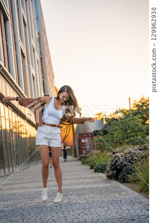 Attractive young woman enjoying her free time at sunset outdoor. Happy girl portrait at summer. Freedom lifestyle summer concept. Sun glow on background. Attractive young woman enjoying her free time at sunset outdoor. Happy girl portrait at summer. Freedom lifestyle summer concept. Sun glow on background. 129962938