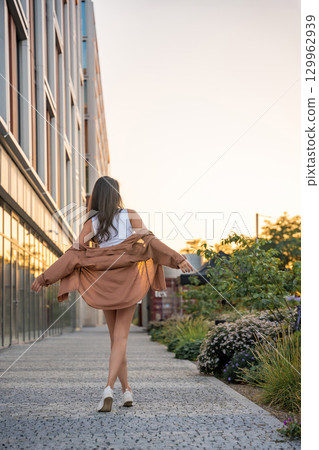 Attractive young woman enjoying her free time at sunset outdoor. Happy girl portrait at summer. Freedom lifestyle summer concept. Sun glow on background. 129962939