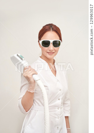 Female caucasian adult using laser hair removal equipment in professional spa 129963017
