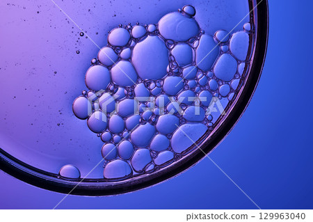 The texture of a cosmetic serum with a trail of bubbles on a purple background. The texture of a cosmetic serum with a trail of bubbles on a purple background. 129963040