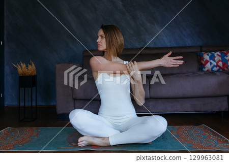 woman doing yoga at home stretching arm 129963081