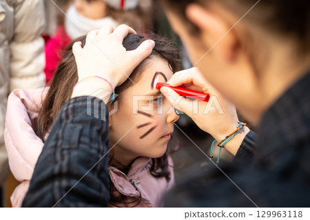 side view of a child face painting at carnival side view of a child face painting at carnival 129963118