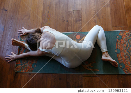 high angle view of a woman at home doing yoga Head to Knee Pose 129963121
