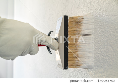 House painter worker painting a wall white. Building. 129963708