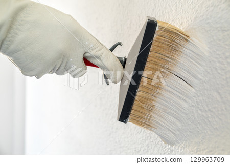 House painter worker painting a wall white. Building. 129963709