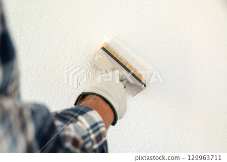 House painter worker painting a wall white. Building. House painter worker painting a wall white. Building. 129963711