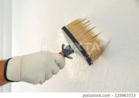House painter worker painting a wall white. Building. House painter worker painting a wall white. Building. 129963713