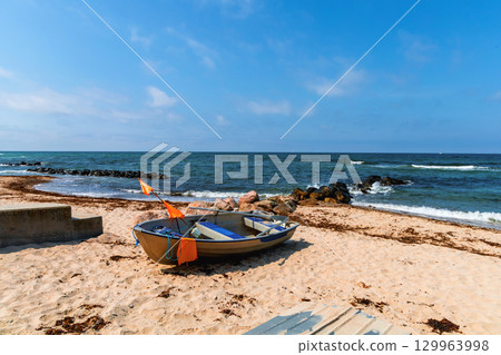 Sea sand beach with boats and blue sky with clouds 129963998