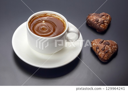 Indulging in hot chocolate paired with heart-shaped cookies on a dark background 129964241