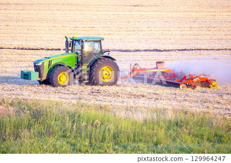 Tractor plowing a field at sunset in rural farmland landscape Tractor plowing a field at sunset in rural farmland landscape 129964247