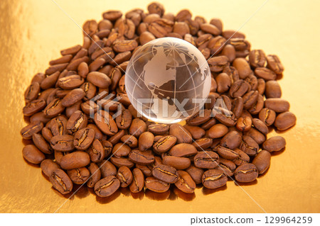 Coffee beans surround a world globe on a golden surface highlighting global coffee trade 129964259