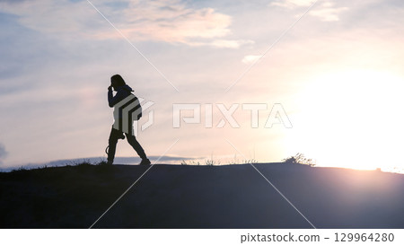 Hiker enjoying a peaceful sunset stroll along a scenic trail in nature 129964280