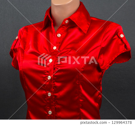 Elegant red satin blouse displayed on a mannequin against a dark background 129964378